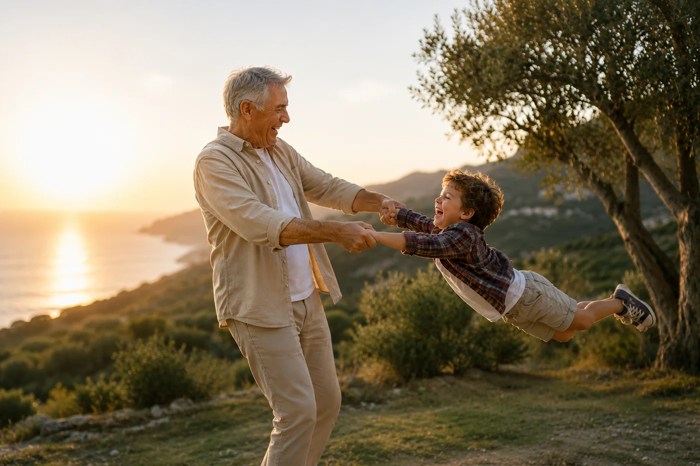 Un grand-père fait tournoyer son petit-fils en riant, face à la mer au coucher du soleil